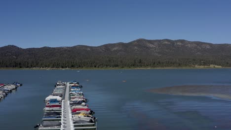 Una-Hermosa-Toma-Aérea-De-Drones-Volando-Hacia-El-Lago-Big-Bear-A-Través-Del-Puerto-Deportivo-Con-El-Horizonte-De-La-Montaña-En-El-Fondo-En-El-Condado-De-San-Bernardino,-California