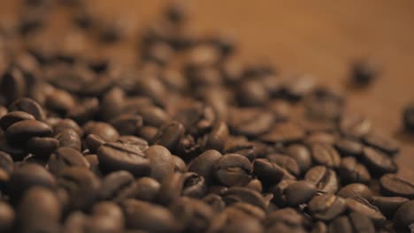 Fresh-coffee-beans-scattered-on-a-wooden-table-slow-motion