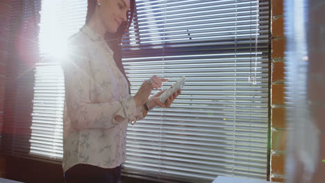 mujer ejecutiva usando tableta digital cerca de la ventana 4k