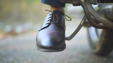 closeup shot of a man trying to kick start an old motorbike