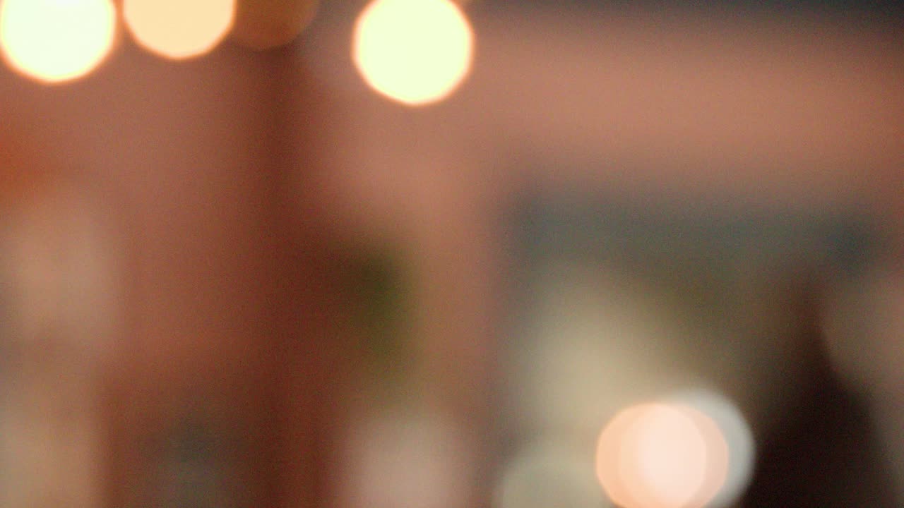 Out-of-focus indoor environment with warm bokeh lights, soft colors, and gentle camera movement