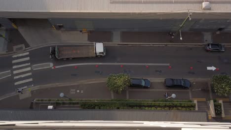 top down view of a small street with cars, truck, and people crossing the road from the zebra cross