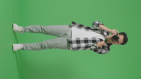 photographer adjusting camera on green screen