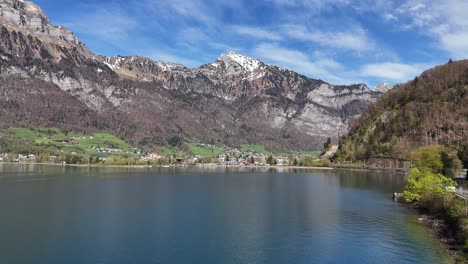 Aerial-approaching-shot-of-small-village-at-Walen-Lake-during-sunny-day-in-Switzerland