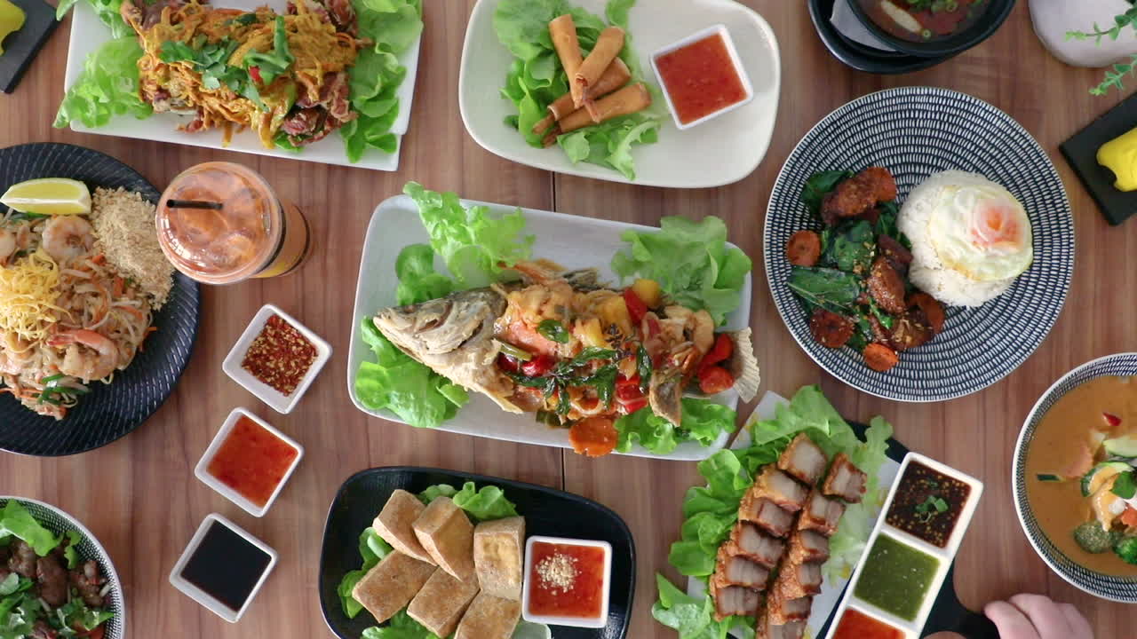 Male hand picking up pork pieces and condiments from thai cuisine food flat lay