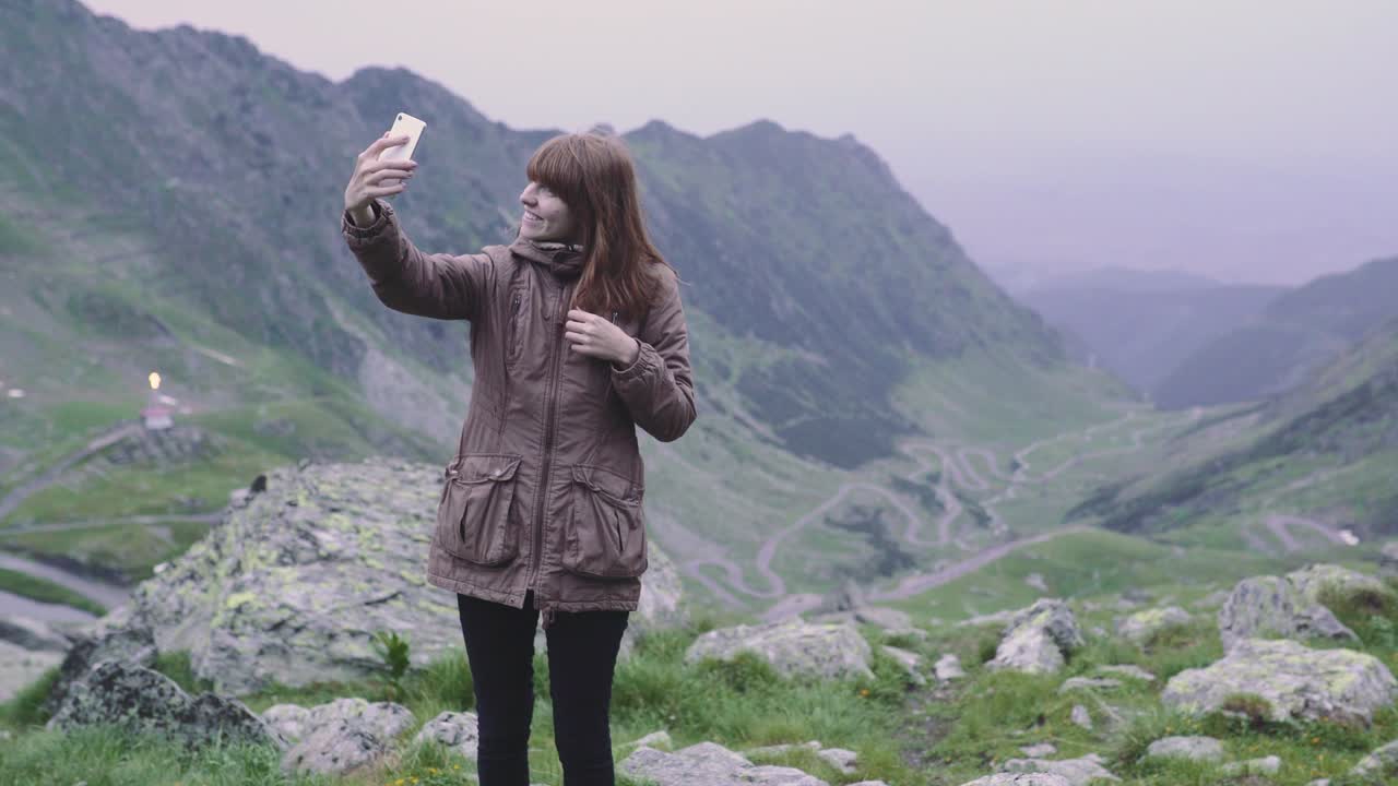 una joven excursionista sube a las montañas y se hace selfies con la cámara de su teléfono inteligente. transfagarasan, montañas de los cárpatos en rumania