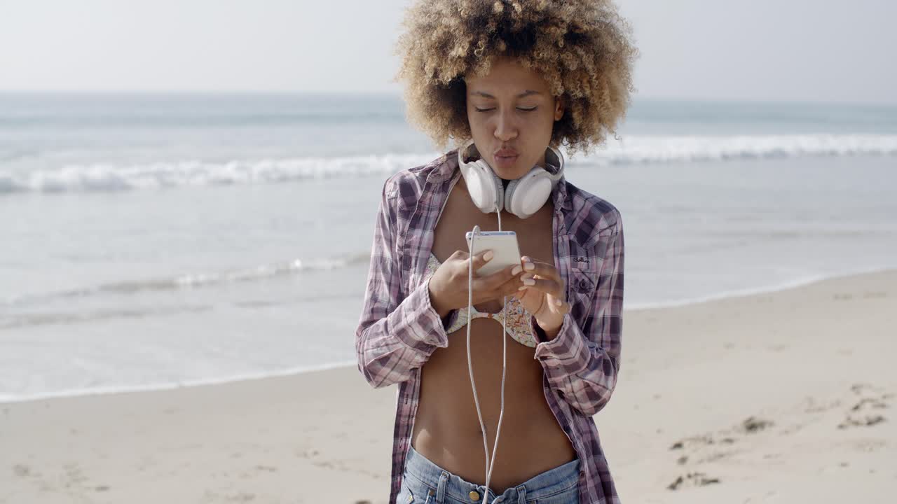 mujer enviando mensajes de texto en la playa