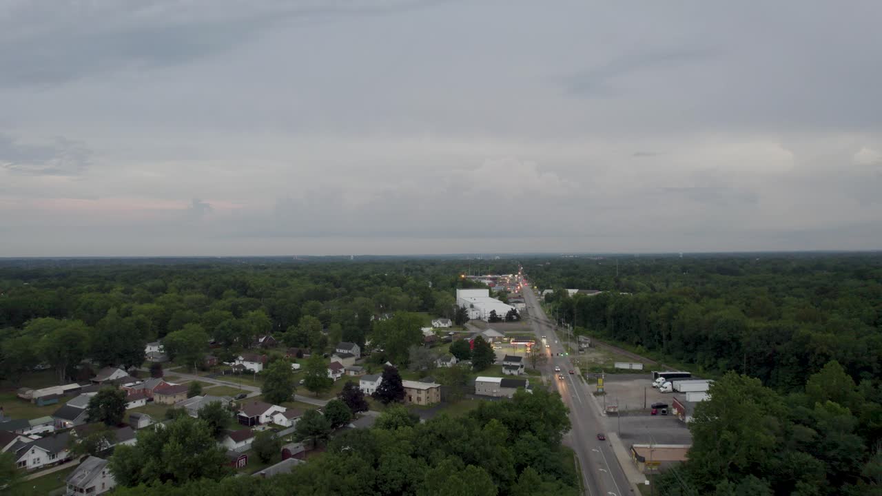 A drone shot of a beautiful busy highway surrounded by beautiful meadow and few small houses are seen alongside of the road