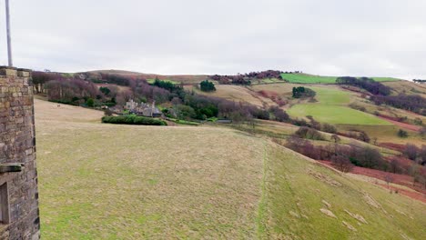 Old-derelict-castle,-monument,-disused-stone-tower,-with-people-walking-around-and-flying-a-drone