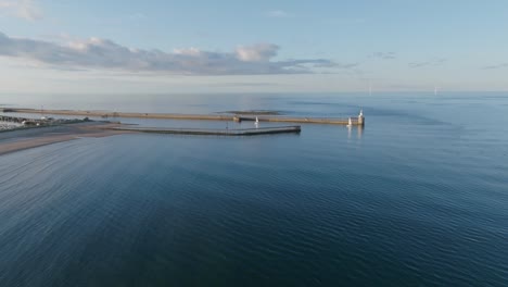 wide angle static drone clip showing curving water currents around harbour walls towards beach