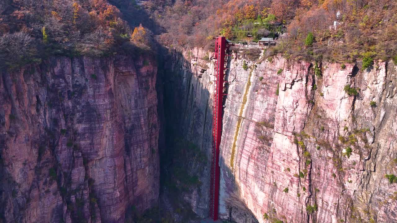 중국 제지안 지방의 시우안 마을의 극적인 절벽을 배경으로 세워진 높은 빨간색 엘리베이터의 넓은 공중 촬영.