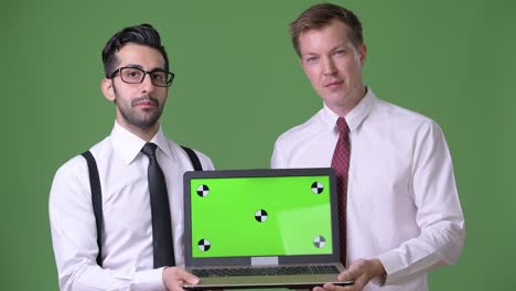 two young multi-ethnic businessmen working together against green background