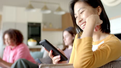 Smiling woman using smartphone while sitting on couch at home