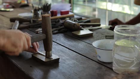 jeweler hand straightening silver metal process by hammering