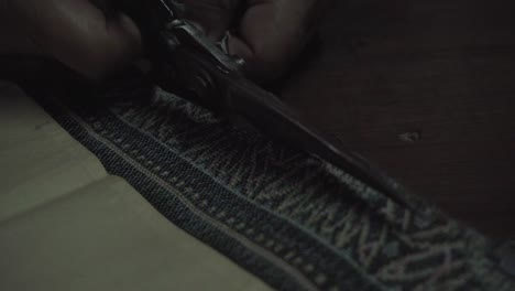 mira de cerca, la vieja sastre usa tijeras para cortar la tela tradicional tailandesa