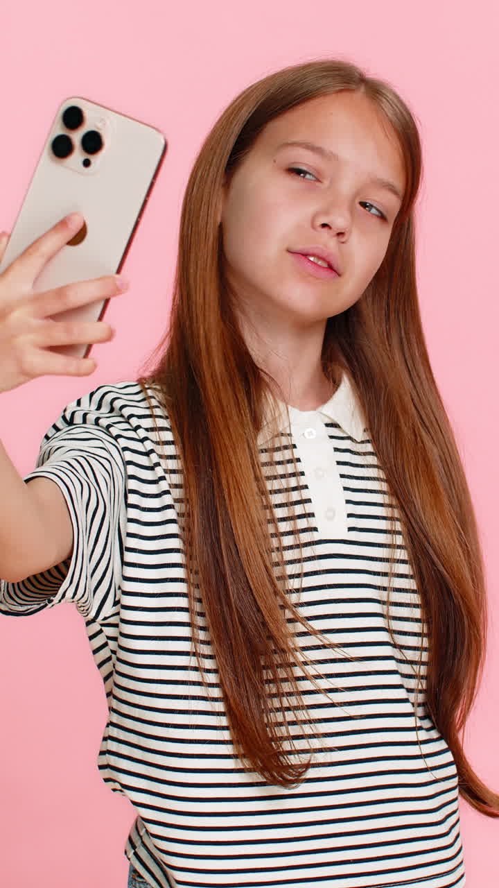 Bambina che si fa allegramente dei divertenti selfie con lo smartphone, ridendo gioiosamente e facendo smorfie