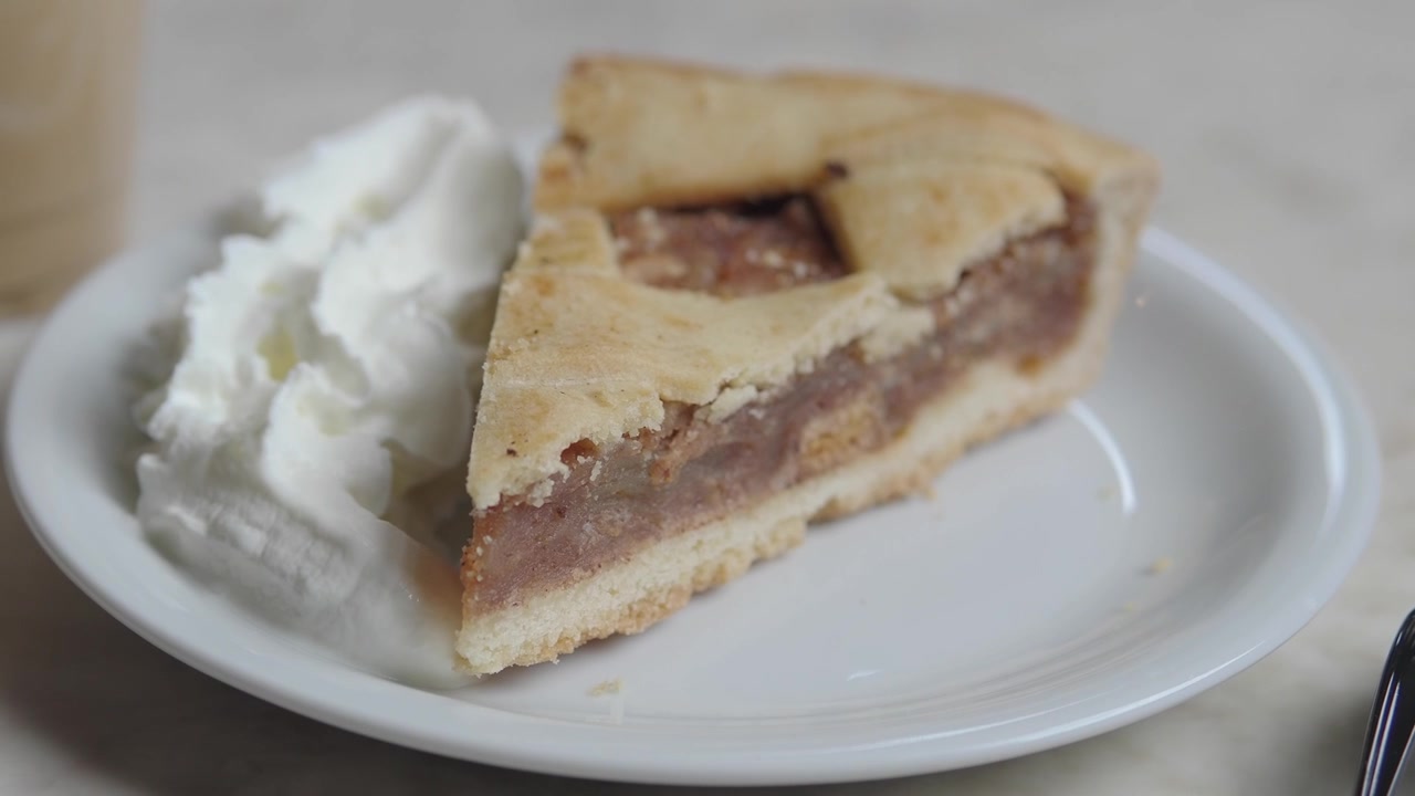 Primo piano di una fetta di torta di mele con panna montata.