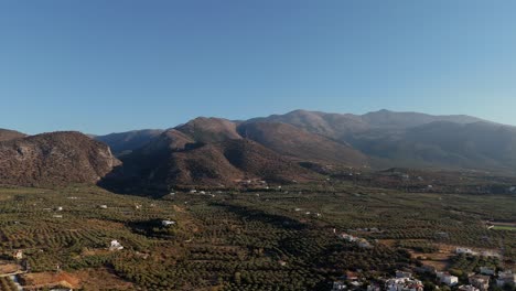 breathtaking aerial view showcasing the mountains of crete, surrounded by lush olive groves and a clear blue sky