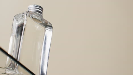 Vertical-video-of-beauty-product-bottle-on-glass-shelf-with-copy-space-on-white-background