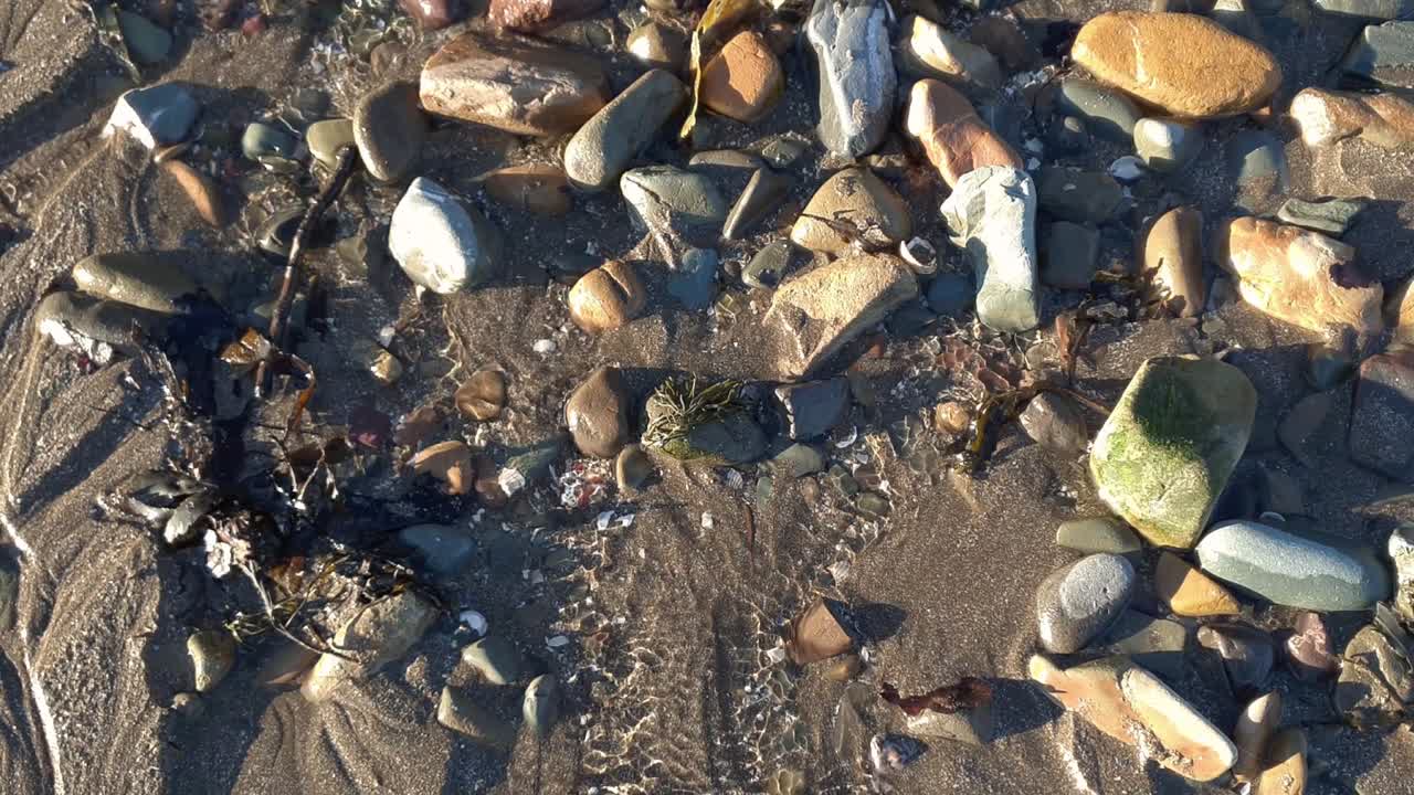 모래 해변에서 바물을 통해 흐르는 작은 물줄기, 바다를 향해