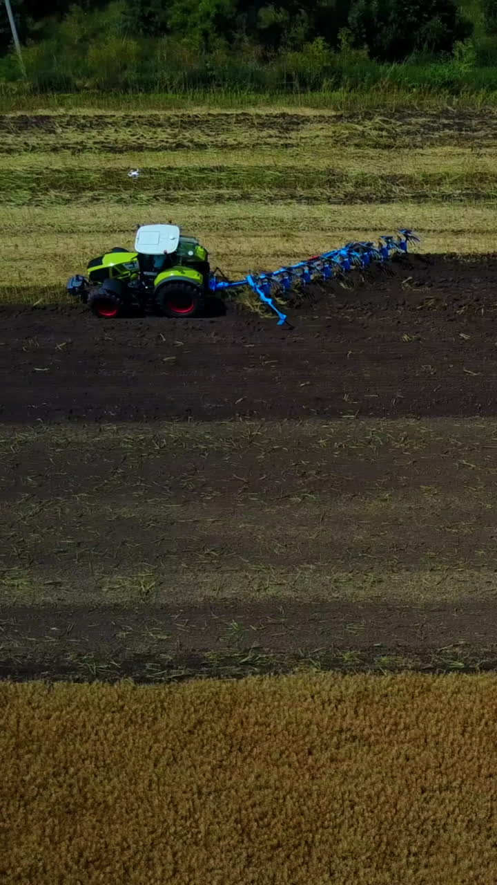 Plow Attached To A Tractor On A Field. Modern farming tractor which plowing agriculturafield Vertical video