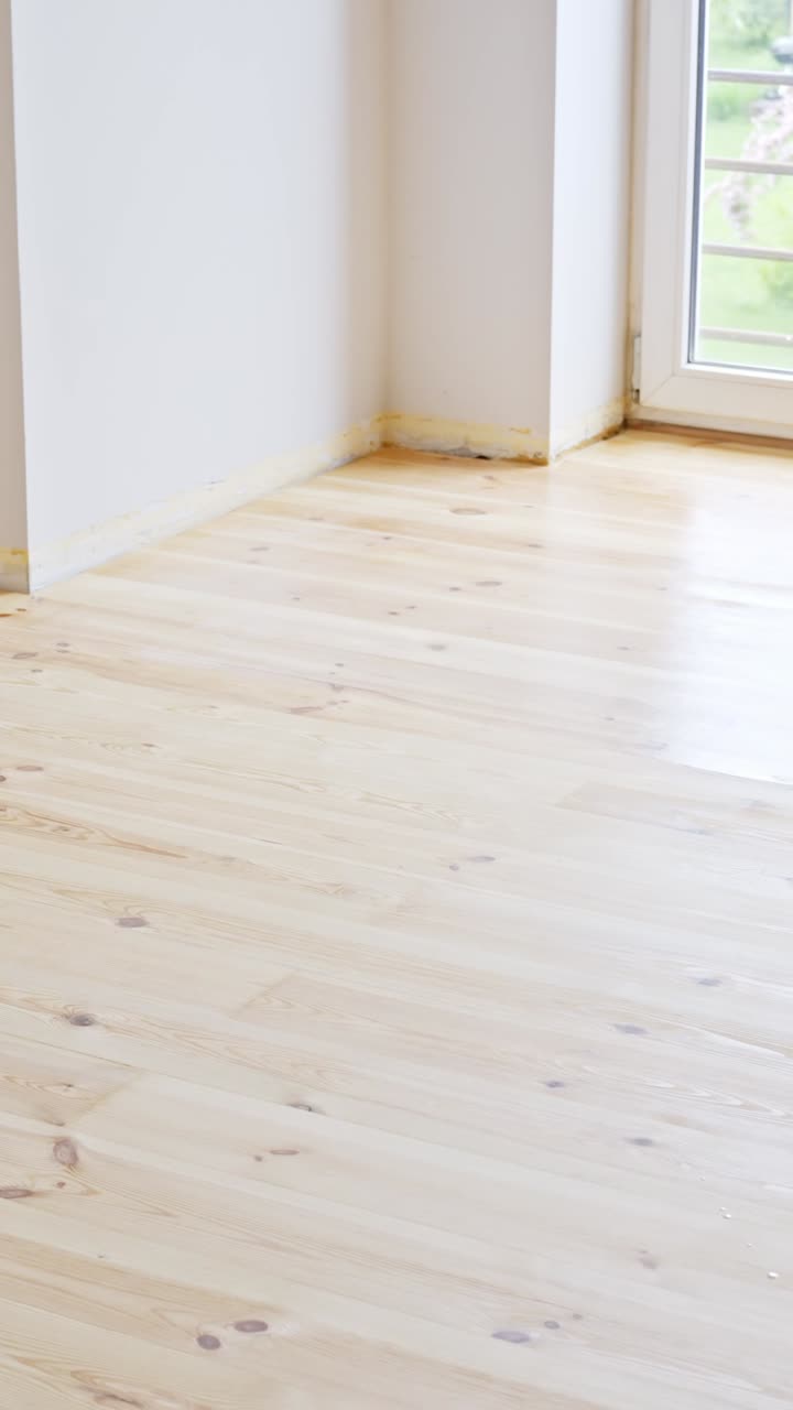 Applying varnish to a hardwood floor with a roller, renovation, vertical