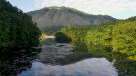 aerial-view-of-the-pristine-Blue-Eye-springs-in-Albania,-showcasing-the-crystal-clear-blue-river-flowing-through-lush-tropical-greenery,-a-true-natural-wonder-and-holiday-destination