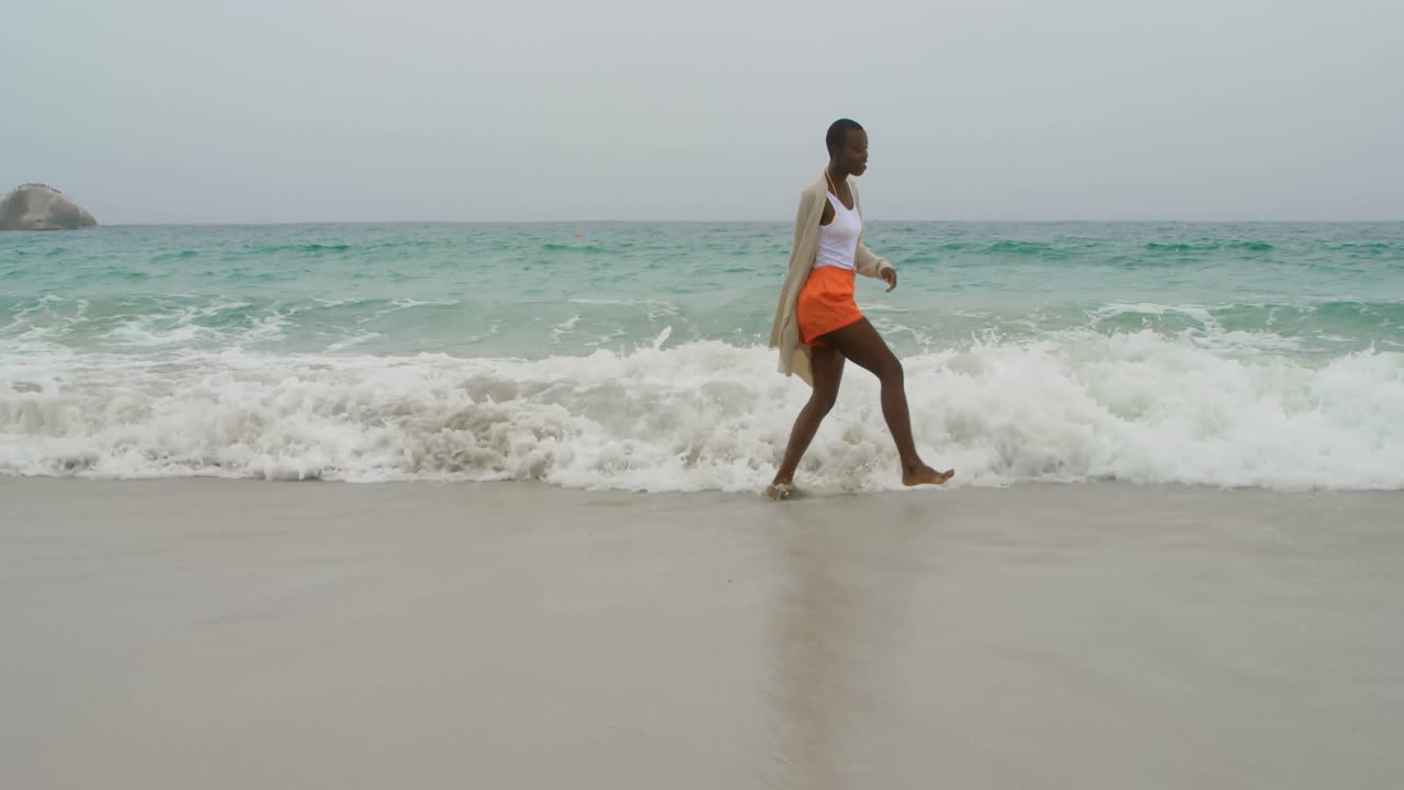 Young African american woman dancing on the beach 4k