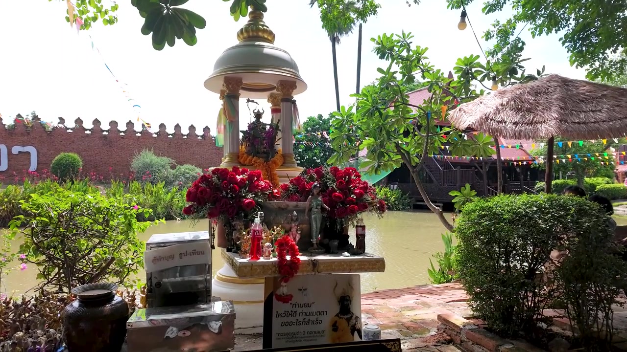 Static medium shot of a Buddhist altar decorated with red roses near a river.