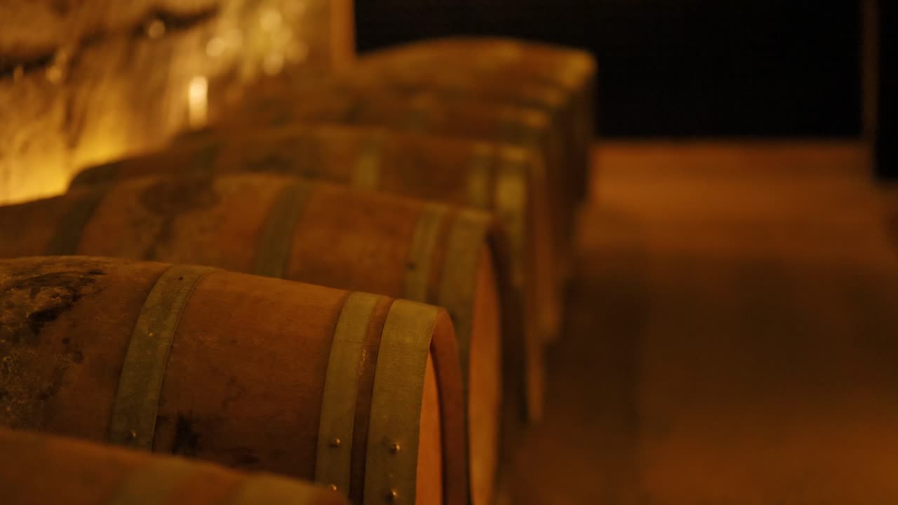 Des rangées de barils de vin dans une cave faiblement éclairée