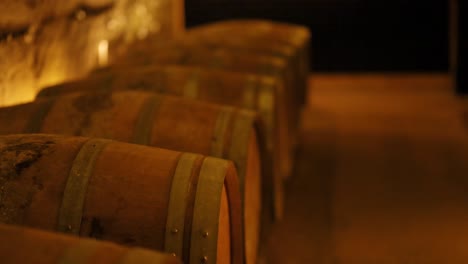 rows of wine barrels in a dimly lit cellar