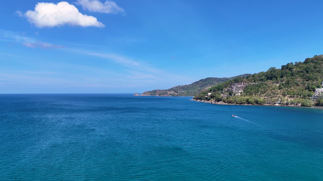 una escena tranquila del océano con aguas azules claras y una lejana costa bajo un cielo brillante en phuket, tailandia