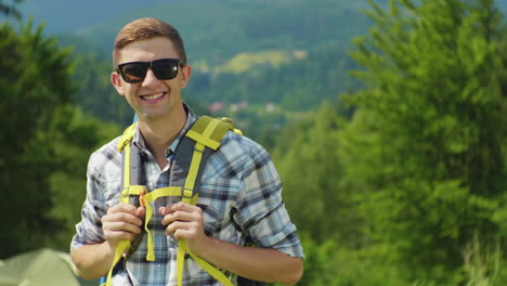 portrait of a young attractive tourist man he is wearing a yellow backpack looking at the camera smi