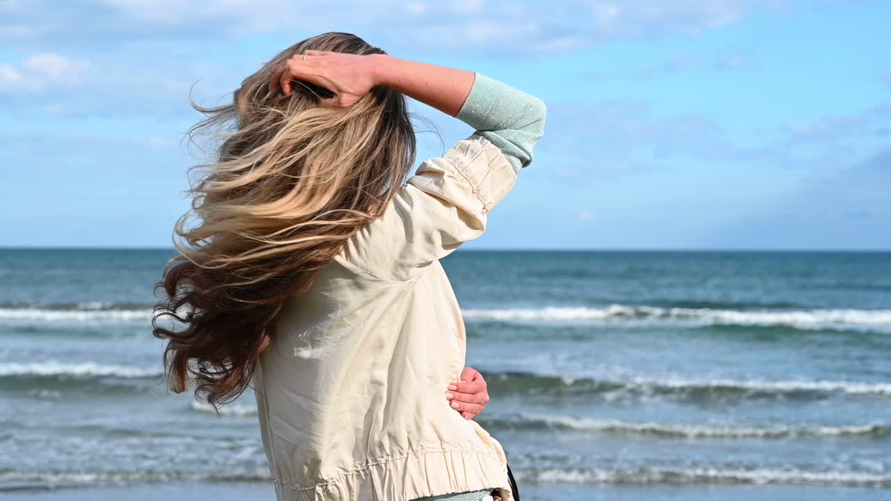 Stylish woman in sunglasses posing on Larnaca beach, Cyprus, with wind blowing through her long hair