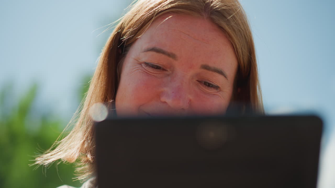 Close up of young girl looking emotional while scrolling through phone outdoors under daylight, expressing quiet reflection, introspection, and connection with digital world