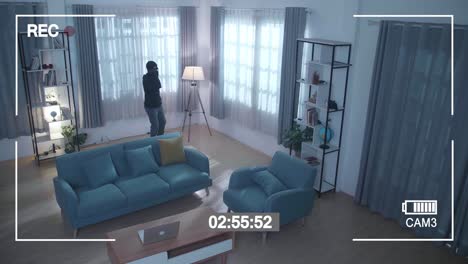 monitor's screen recording a thief holding flashlight stealing a laptop in someone's house before walking away