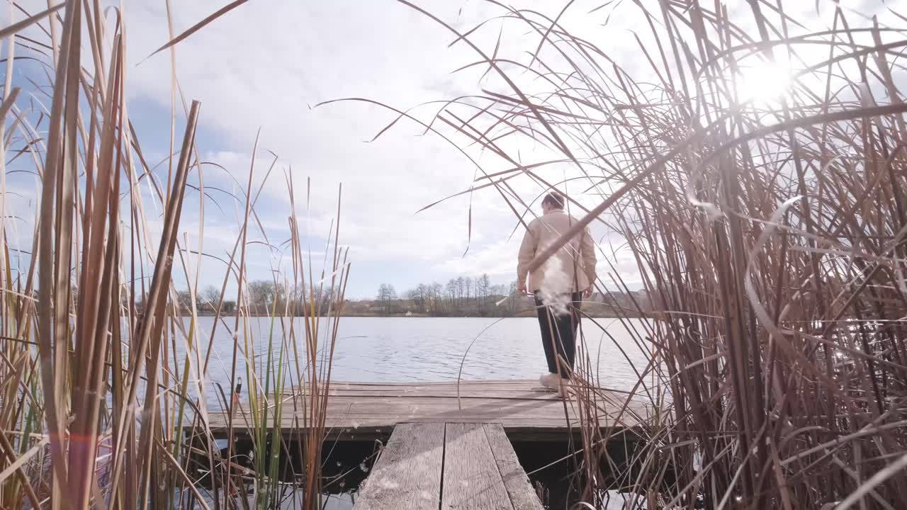 Man walks on wooden pier in a autumn day