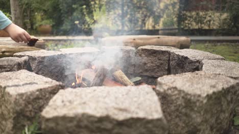 Feeding-the-campfire-flame-with-leaves