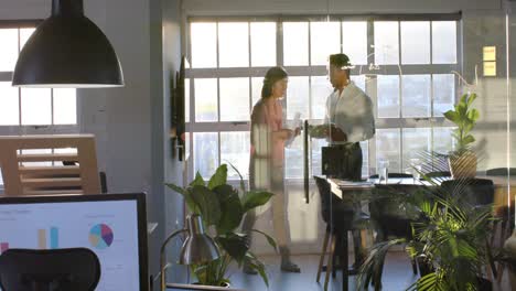 Diverse-male-and-female-colleague-with-documents-and-tablet-discussing-in-meeting-room,-slow-motion