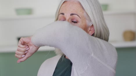 portrait of senior caucasian woman coughing or sneezing into her arm