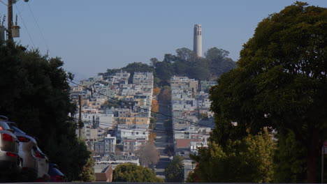 the crooked lombard street with coit tower visible in the distance in san francisco, california - wide shot