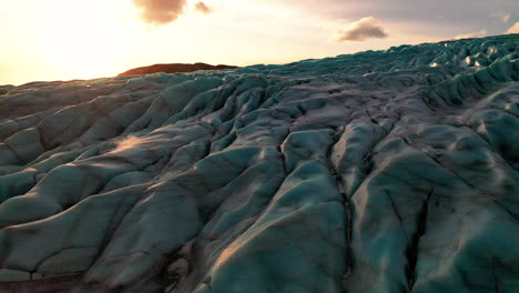 the amazing ice-carved landscape at falljokull glacier outlet in south iceland on a sunset - ascending drone shot