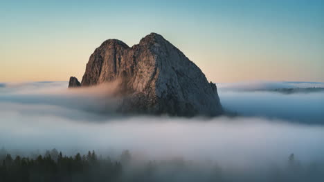 mountain peak emerging through a sea of fog at sunrise or sunset