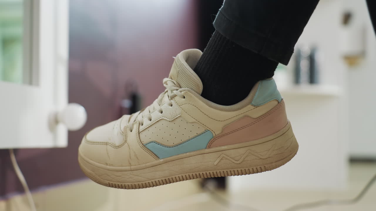 가벼운 신발의 평온함, 베이지색 스니커즈와 은은한 조명 효과로 포착한 차분한 분위기, 평화로운 휴식 시간에 창가에 걸려 있는 밝은 베이지색 스니커즈를 보여주는 고요한 스냅 사진