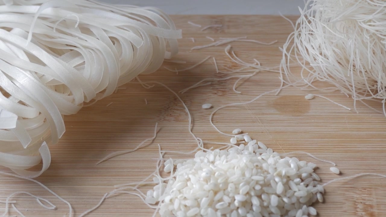 Tagliatelle di riso su un tagliere di legno, evoca semplicità e arte culinaria