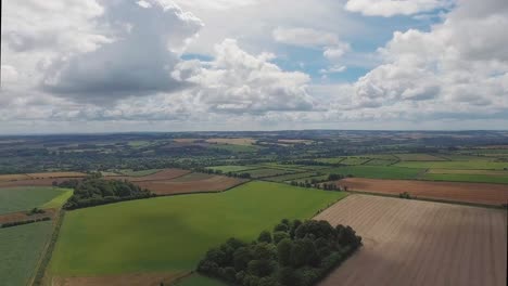 an aerial shot of the english countryside, looking down on fields below as clouds pass over in the uk