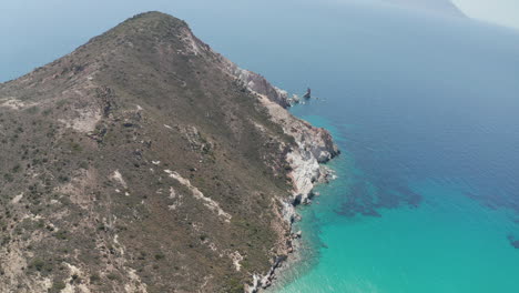 Toma-Aérea-Amplia-De-La-Montaña-De-La-Isla-Griega-En-Milos-En-Verano-Con-El-Mar-Egeo-Azul-Turquesa