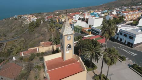 Forwarding-Aerial-Dolly-Shot-of-Village-Passing-by-Church-Steeple,-Coast-of-Spain-Daytime