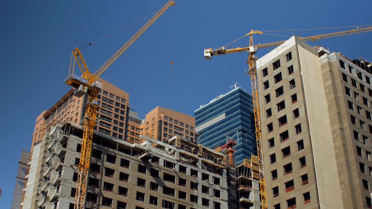 panorama de las cimas de la construcción incompleta de edificios con grúas en el día de verano