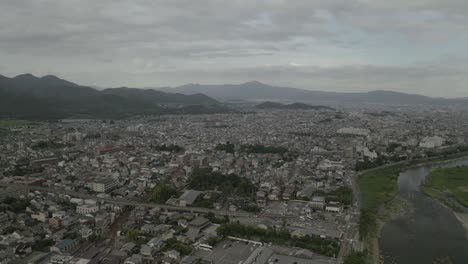 Aerial-Drone-Shot-of-Kyoto-at-Sunset-near-a-river,-Japan,-Asia